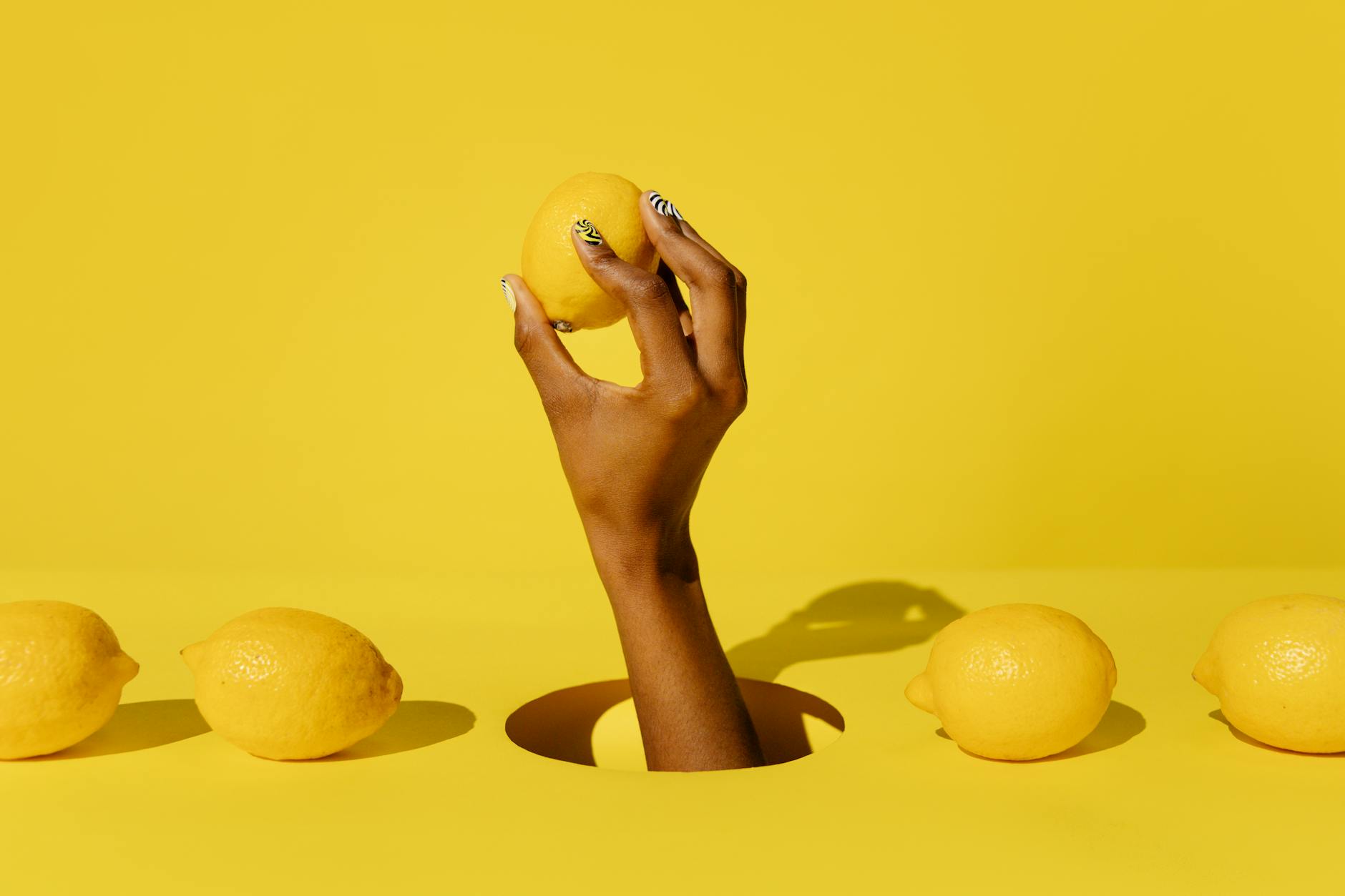 A fresh lemon held against a vivid yellow background, representing renewal and vitality during recovery.