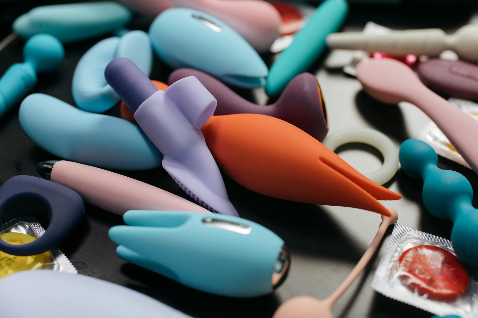 Woman holding blue and pink clitoral vibrators with a thoughtful expression