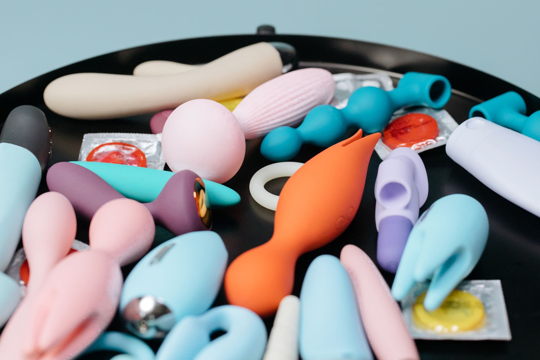 Woman holding blue and pink silicone vibrators, contemplating pleasure options for couples