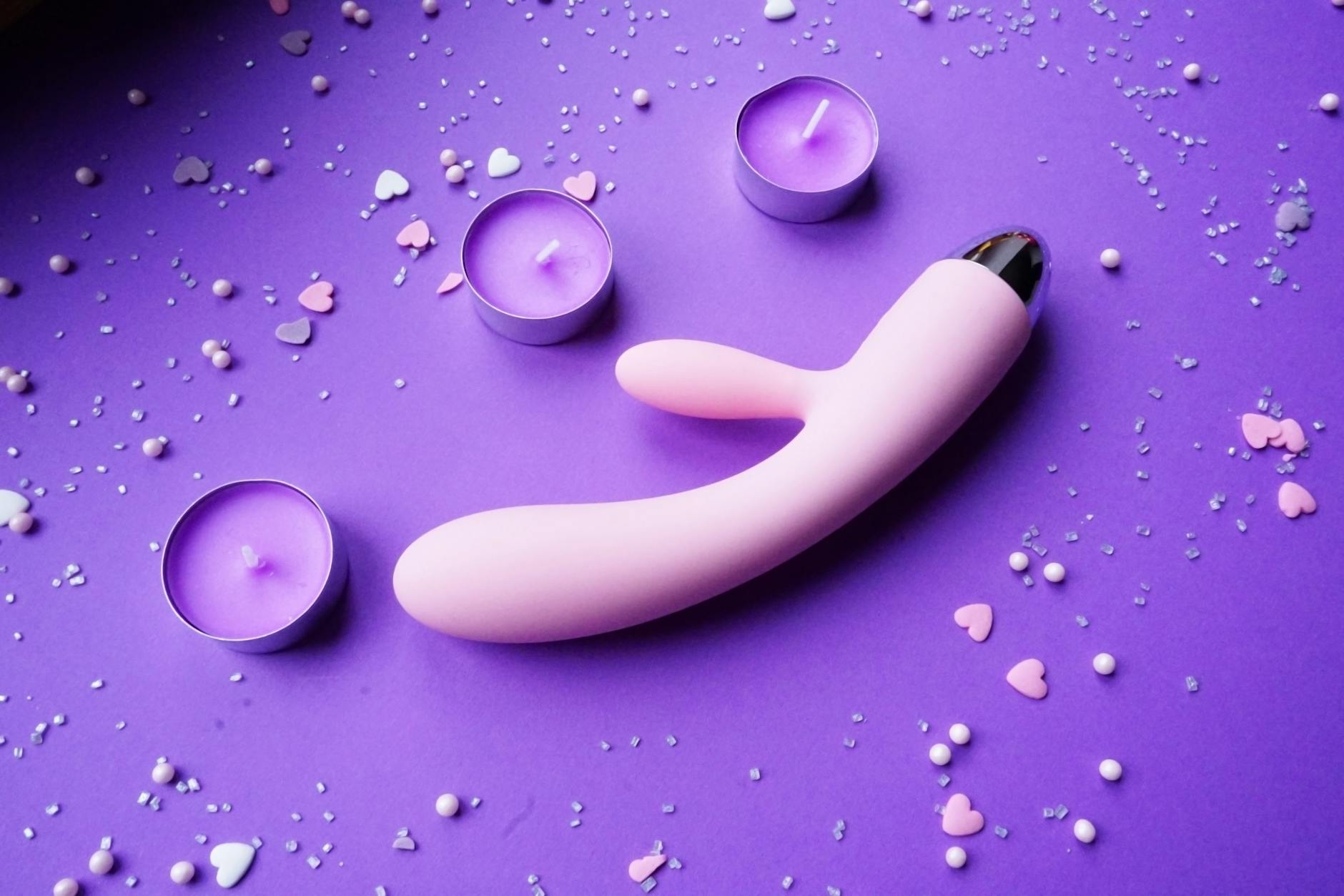 Lemon clitoral vibrator on a soft background with candles and heart confetti, symbolizing self-care and stress relief
